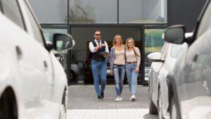Twee vrouwen bekijken leaseopties bij autodealer met verkoper – advies over passende leasevormen